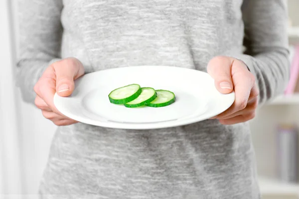 Female hands holding a plate cucumber — Stock Photo, Image