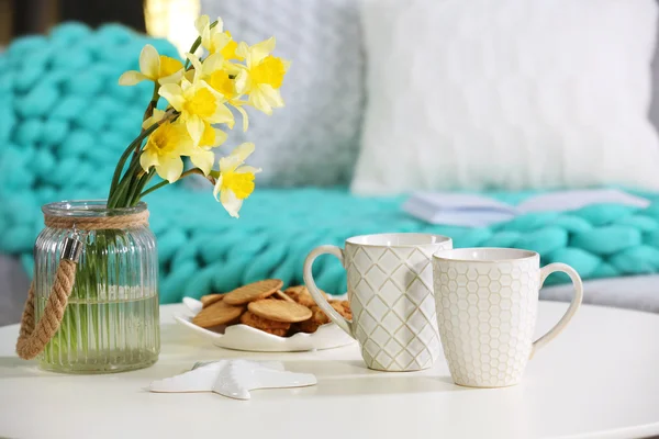 Cups with cookies and bouquet of narcissus — Stock Photo, Image