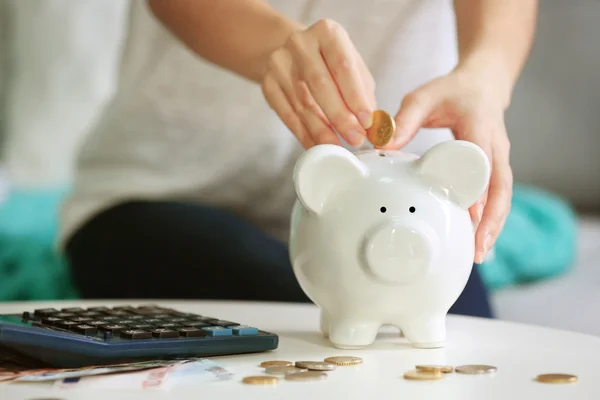 Hand putting coin into piggy bank — Stock Photo, Image