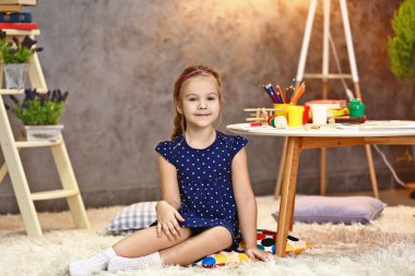 Halı üzerinde oturan güzel küçük kız