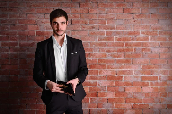 Hombre atractivo en un traje que muestra un bolso — Foto de Stock