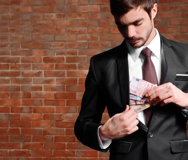 Hombre atractivo escondiendo billetes en euros —  Fotos de Stock