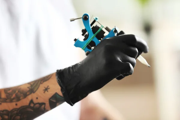 La mano del hombre que sostiene la máquina del tatuaje — Foto de Stock