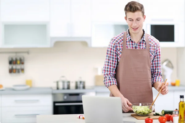 Muž vaření zeleninový salát v kuchyni — Stock fotografie