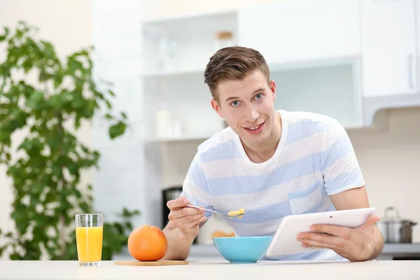 Homem com tablet e tomando café da manhã — Fotografia de Stock