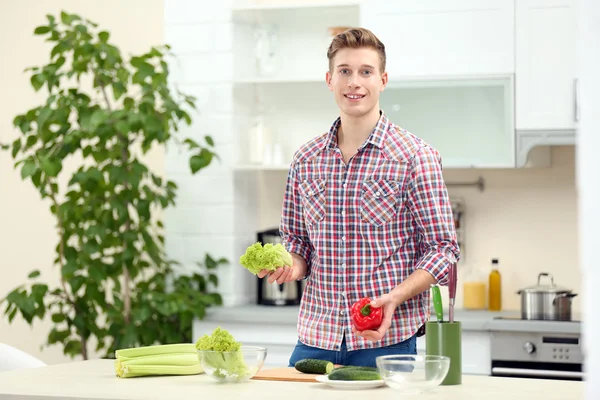 Uomo con verdure in cucina luminosa — Foto Stock