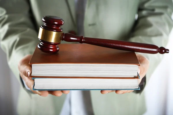 Man holding books with wooden gavel — Stock Photo, Image