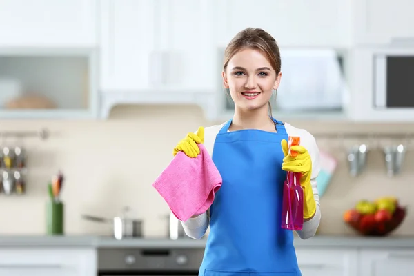 Il concetto di pulizia. Ritratto di giovane donna con liquido di lavaggio e straccio sullo sfondo della cucina — Foto Stock