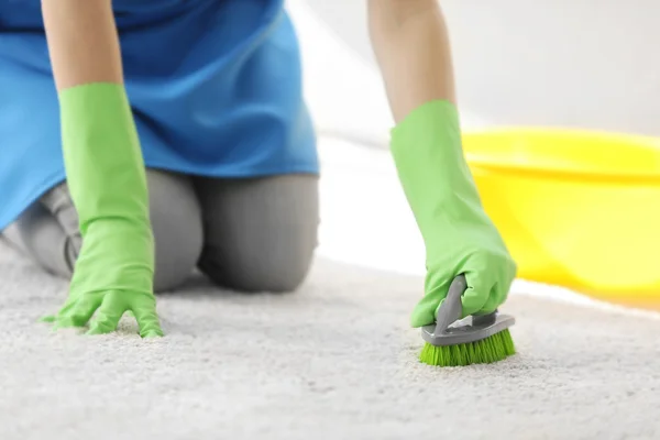 Mladá žena čistí koberec — Stock fotografie