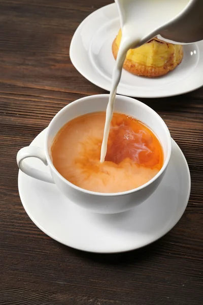 Susu dituangkan ke dalam secangkir teh — Stok Foto