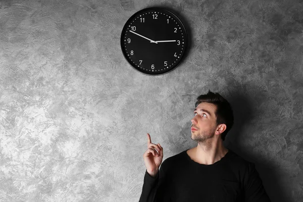 Hombre parado al lado de un reloj — Foto de Stock