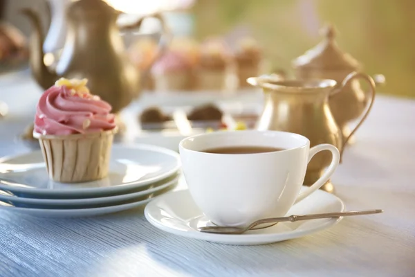 Cupcake met roze crème en kopje thee — Stockfoto