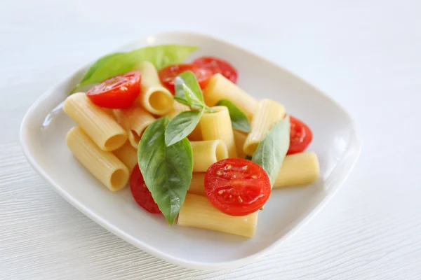 Taze domates ve fesleğen beyaz tabakta ile haşlanmış rigatoni makarna — Stok fotoğraf