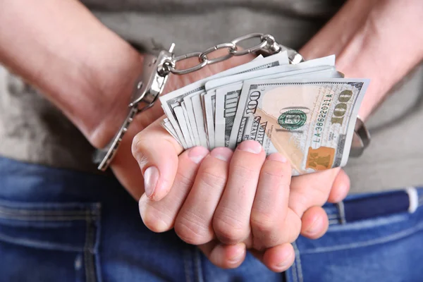 Egy férfi bilincsben, kezében dollár bankjegyekkel a háta mögött, közelről — Stock Fotó