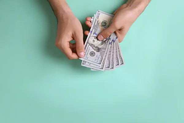 Mãos masculinas contando notas de dólar em fundo turquesa — Fotografia de Stock