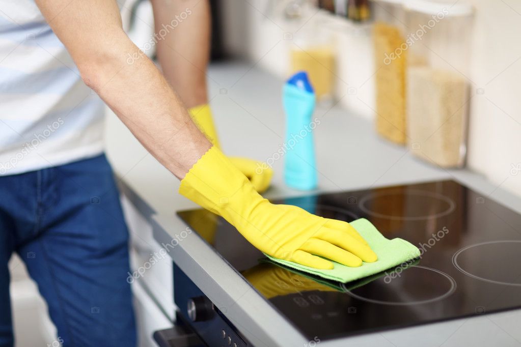 Man cleaning electric hob Stock Photo by ©belchonock 108216560