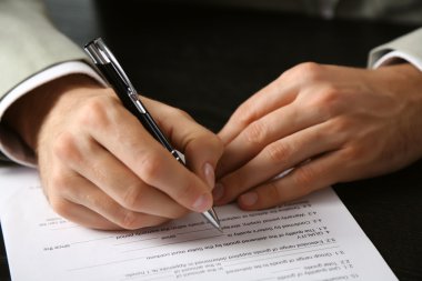 Male hand with pen signing document clipart
