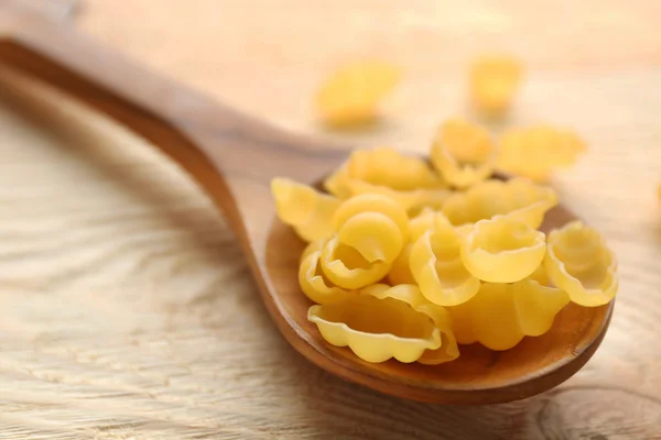 La pasta seca de ñoquis en la cuchara de madera sobre la mesa — Foto de Stock