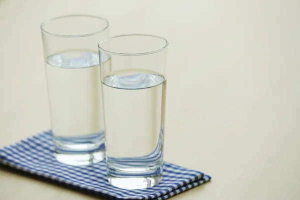 Glasses of pure water on light wooden table — Stock Photo, Image