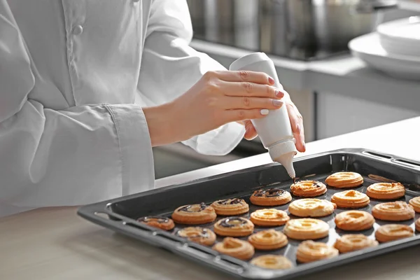 Vrouwelijke handen decoreren gebakken koekjes — Stockfoto