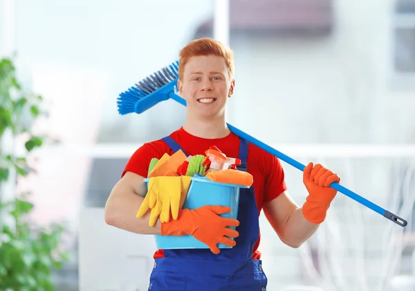 Joven conserje sosteniendo productos de limpieza — Foto de Stock