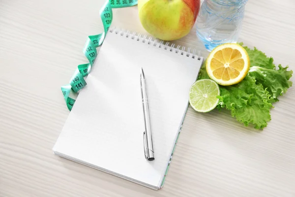 Notebook, measuring tape and healthy food — Stock Photo, Image