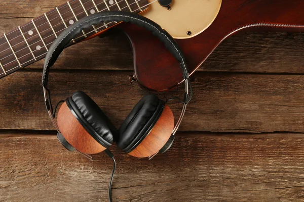 Sluchátka a kytara na dřevěné — Stock fotografie