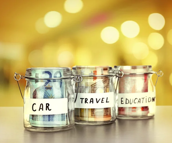 Jars for different needs full of banknotes — Stock Photo, Image