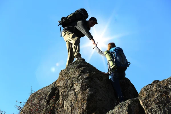与阳光之间两名登山者援助之手 — 图库照片