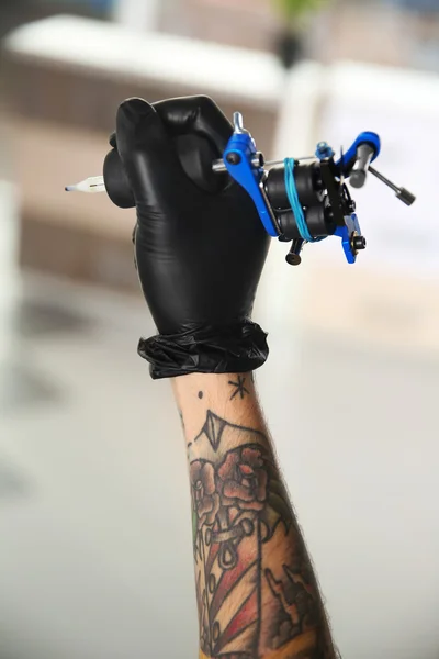 La mano del hombre que sostiene la máquina del tatuaje —  Fotos de Stock