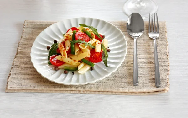 Kokt penne pasta med tomater, franska bönor och rucola på vit platta — Stockfoto