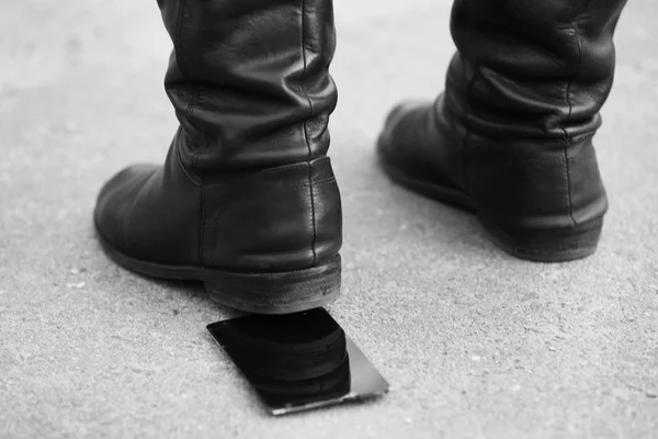 Botas femininas esmagando um telefone celular — Fotografia de Stock