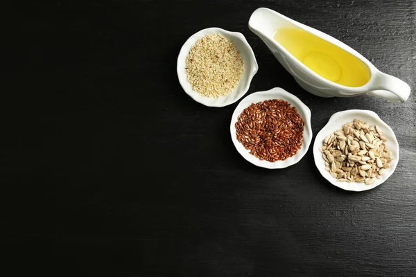 Different kinds of seeds and oil on wooden table — Stock Photo, Image