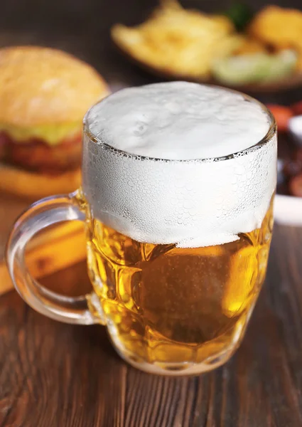Glazen mok light bier met snacks op donkere houten tafel, close-up — Stockfoto