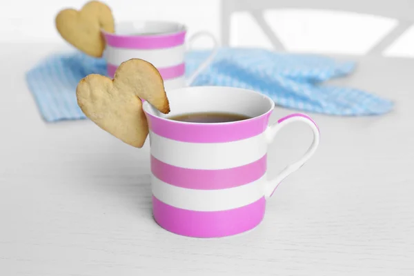 Galleta en forma de corazón en taza de café en primer plano de la mesa — Foto de Stock