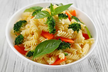 Düdük makarna havuç, brokoli ve beyaz tabakta fesleğen ile haşlanmış