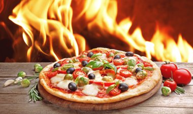 Delicious hot pizza on wooden table against fire flame background clipart