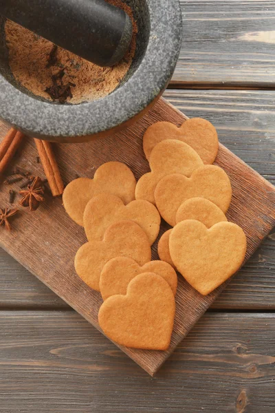 Heart shaped biscuits and cinnamon on cutting board, top view — Stock Photo, Image