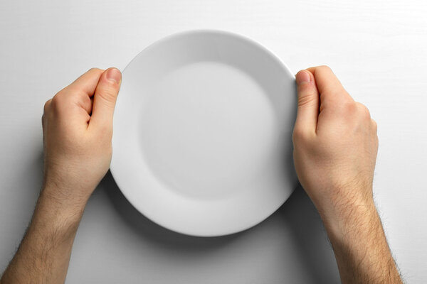 Мужские руки с белой тарелкой
