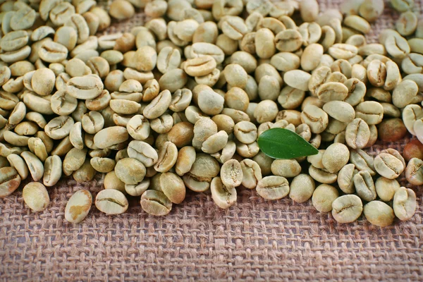 Green coffee beans on sackcloth material. — Stock Photo, Image