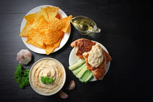 Keramikskål av god hummus med chips och persilja på table — Stockfoto