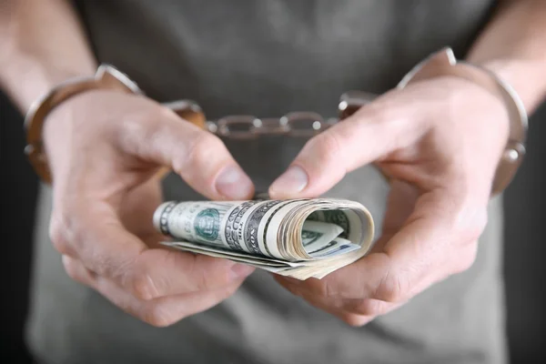 Man in handcuffs holding dollar banknotes — Stock Photo, Image