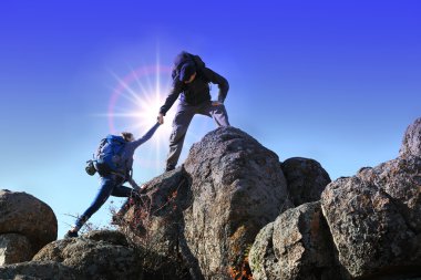 Helping hands with sunlight between two climbers clipart