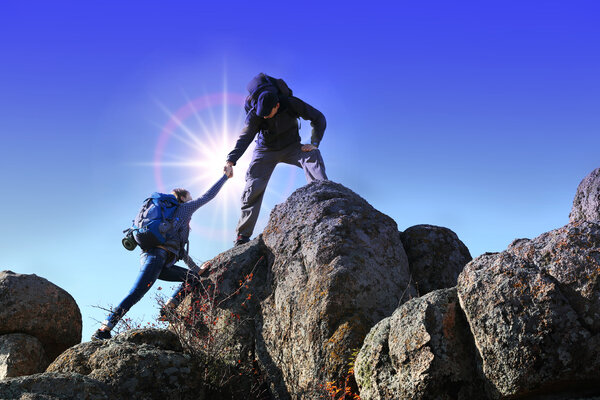Помогая рукам солнечным светом между двумя альпинистами

