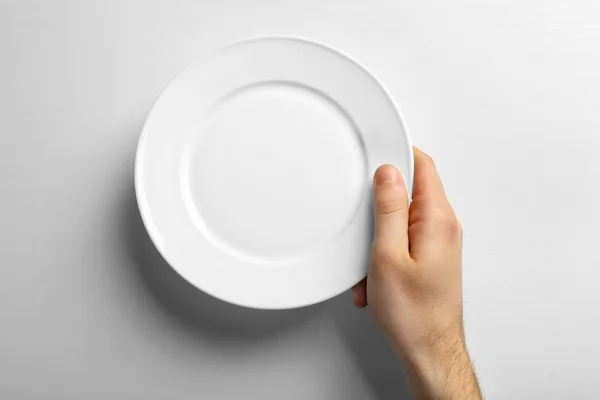 Male hand holding white plate — Stock Photo, Image