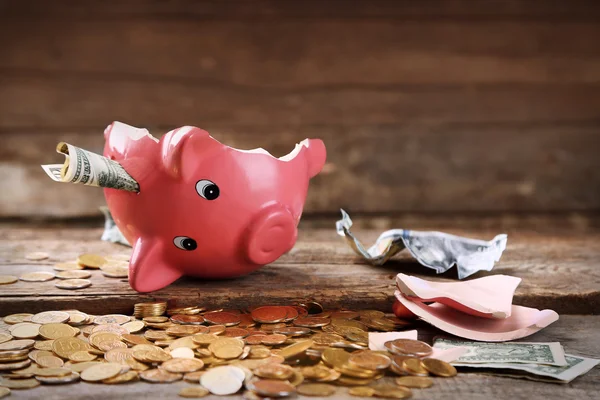 Broken piggy bank with cash and coins — Stock Photo, Image