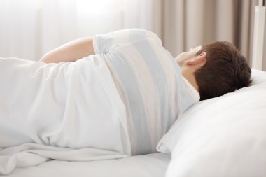 Genç adam yatakta uyuyor.