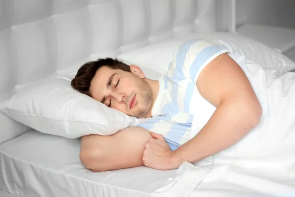 Junger Mann schläft im Bett — Stockfoto