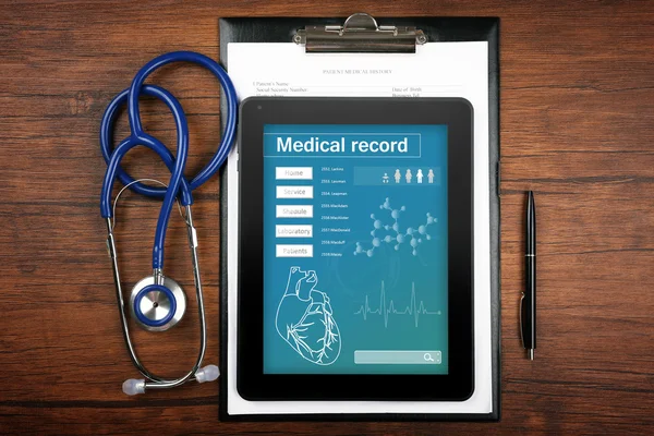 Orvosi rekord a Tablet PC képernyőjén sztetoszkóp, fából készült háttér — Stock Fotó