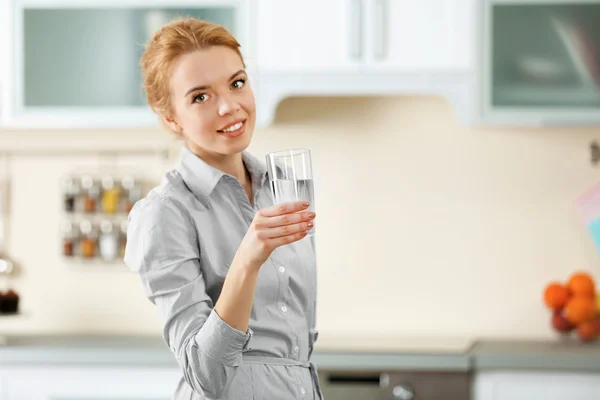 Mujer joven en la cocina agua potable — Foto de Stock